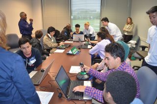 Vencore volunteer Johnny Martin (standing left) leads flight simulations for Thomas A. Edison AVID students at the Space Group STEM event on May 6, 2016.